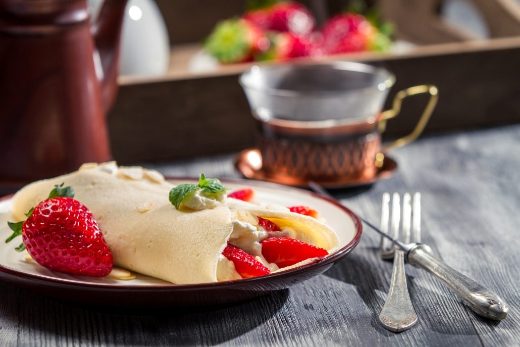 A beautifully presented crepe with strawberries and cream on a plate, enjoyed at The Crepe Shack in Aspen Coffee Shops.