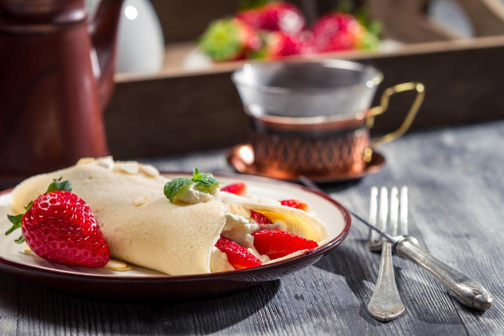 A beautifully presented crepe with strawberries and cream on a plate, enjoyed at The Crepe Shack in Aspen Coffee Shops.