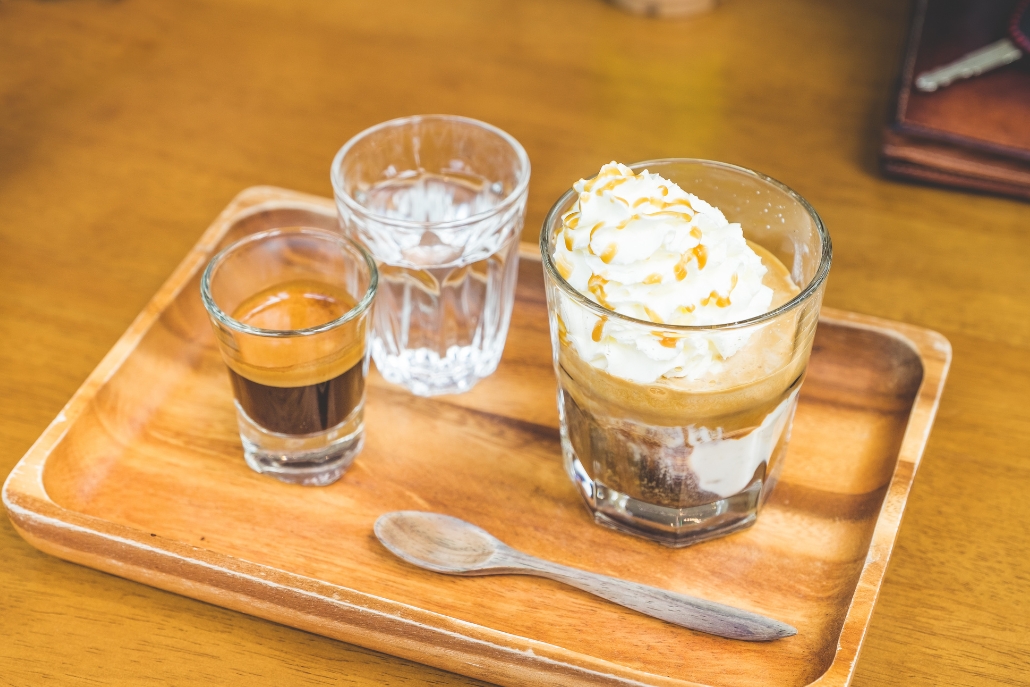On a wooden tray, a glass of coffee sits alongside ice cream, highlighting the affogato served at Unravel Coffee & Bar.