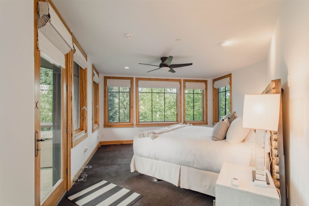 A cozy Chalet Spruce bedroom featuring a bed, a window, and a ceiling fan, adorned for a festive Christmas atmosphere.