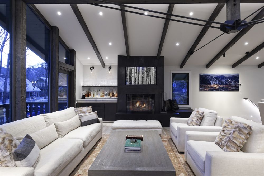 A cozy Aspen living room featuring white couches and a warm fireplace, adorned for a festive Christmas atmosphere.