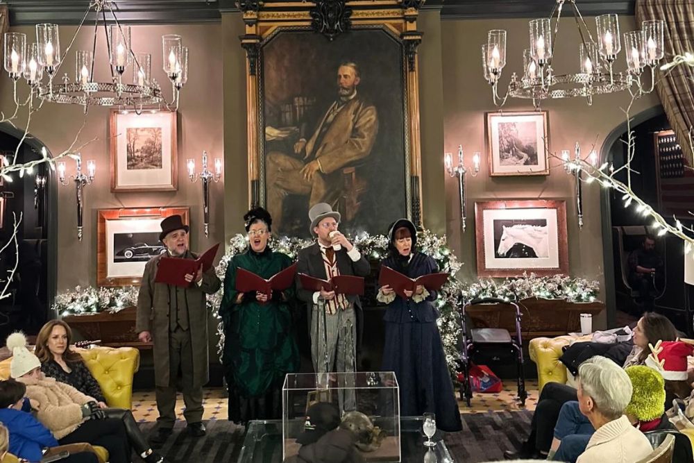 A group of people perform christmas caroling at Hotel Jerome