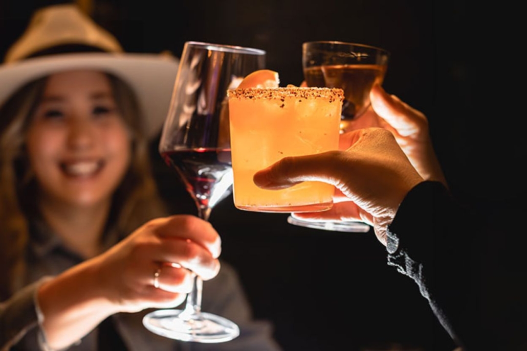 A group of women toast with wine glasses and enjoys musical performances at the bar in Aspen.