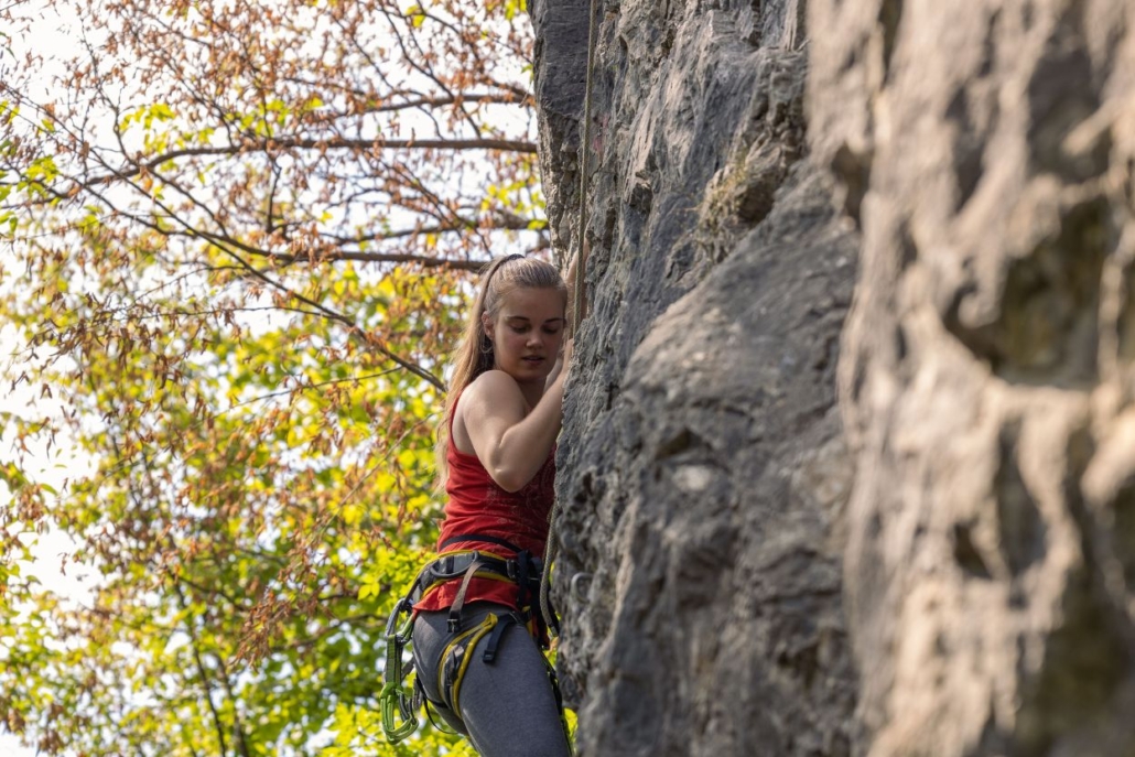 A determined woman climbs a rock wall, showcasing her strength and resilience at Independence Pass.