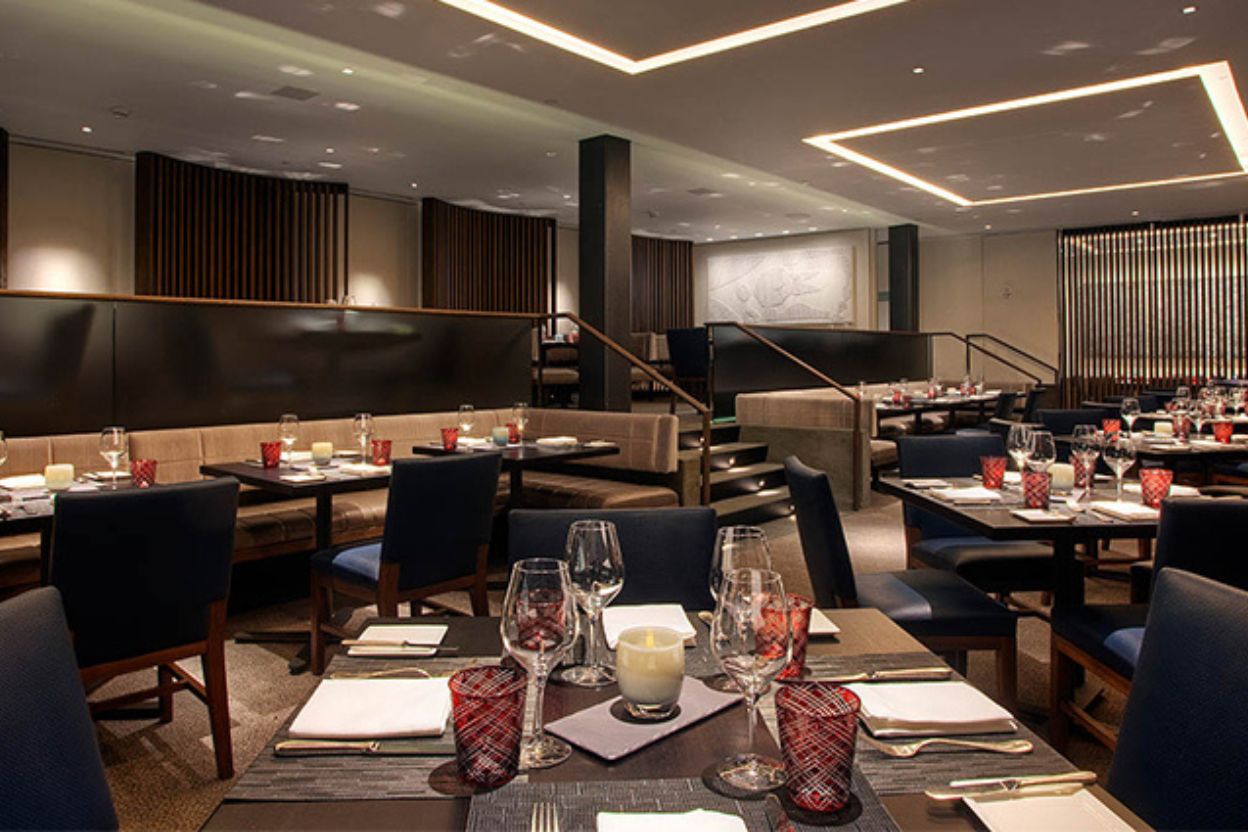 Interior view of a restaurant with tables and chairs positioned in the center, highlighting the stylish element 47 Aspen theme.