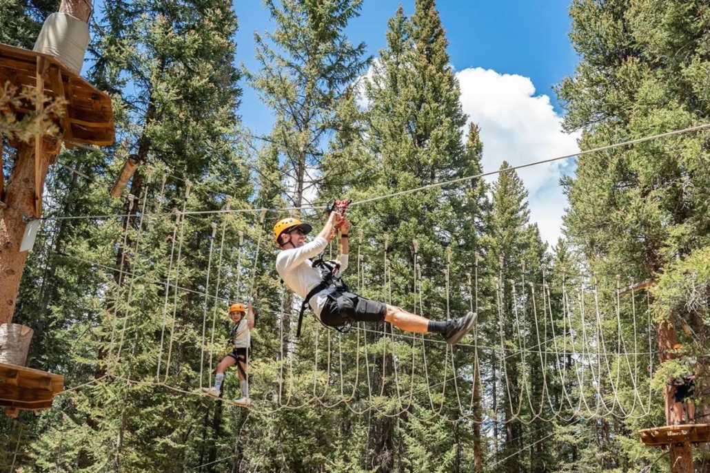 A man experiences the thrill of zip lining amidst the vibrant aspen trees of the Lost Forest Treeline Trial.