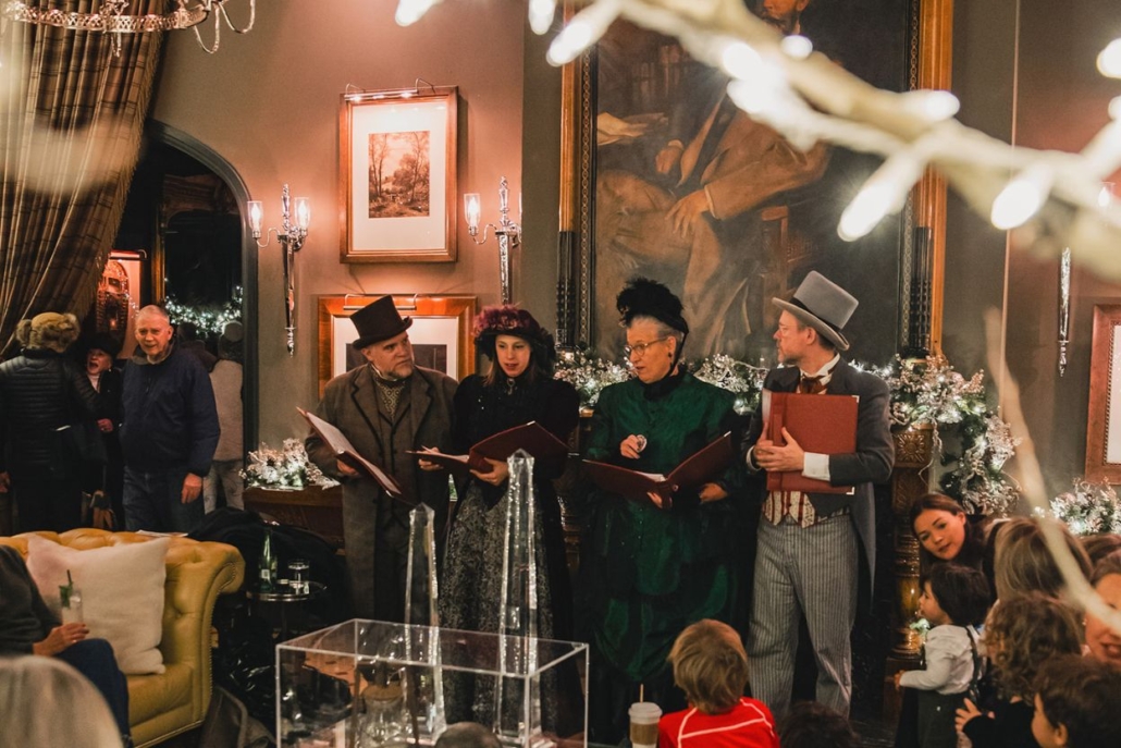 A festive gathering of people around a beautifully decorated Christmas tree in a cozy Aspen room.