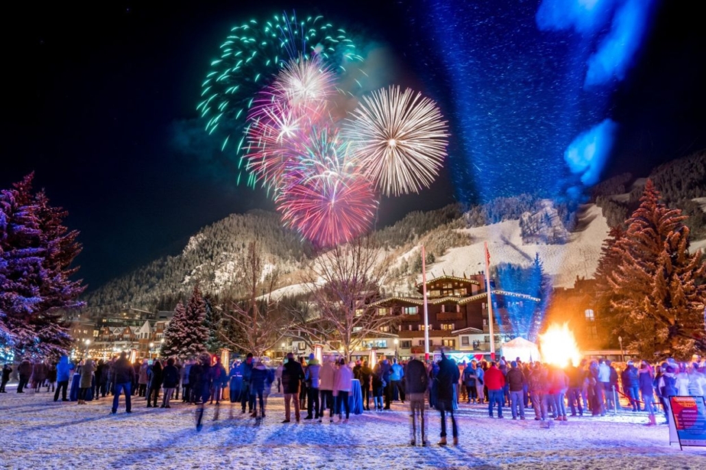 Colorful fireworks illuminate the night sky over a joyful crowd during the Wintersköl Festivities in Aspen.