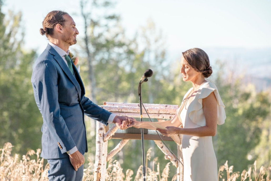 A bride and groom exchange heartfelt vows surrounded by stunning mountain scenery during their aspen elopement.