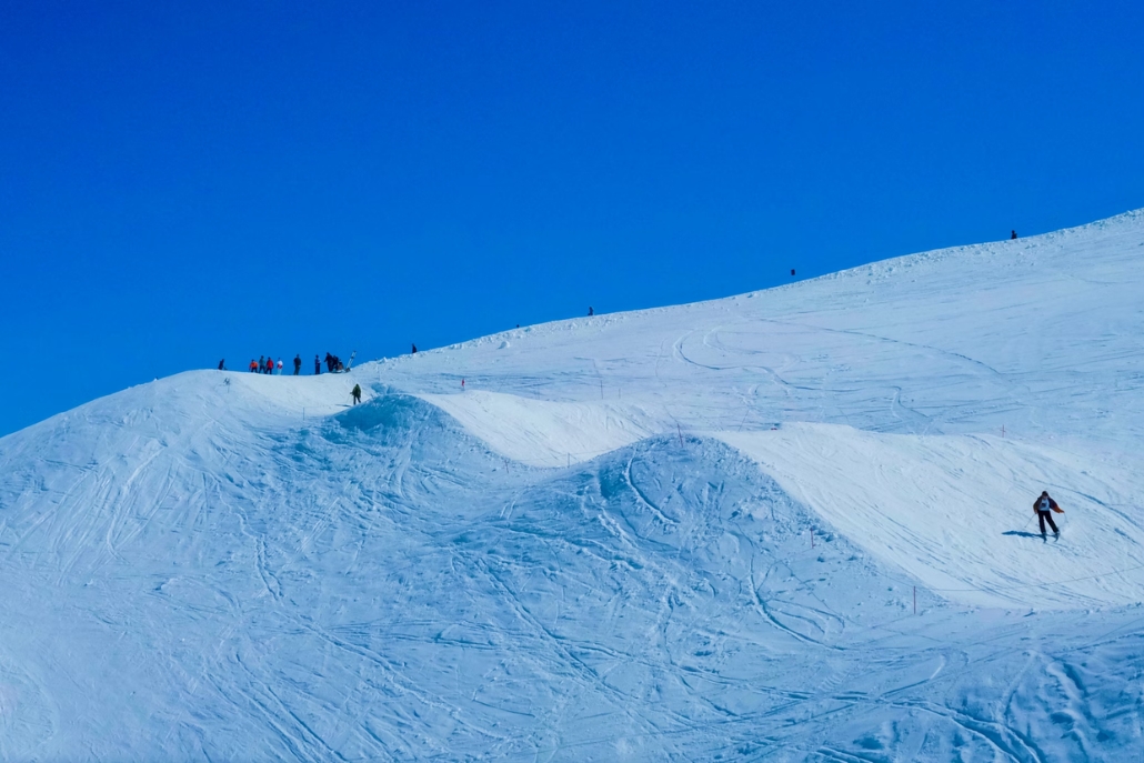 A group of skiers and snowboarders descends a snow-covered slope at Aspen Highlands ski resort in Colorado.