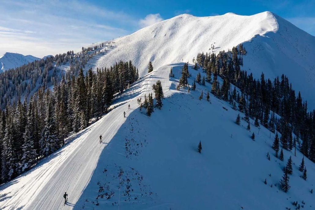 A skier gracefully descends a snowy slope at Aspen Highlands, surrounded by majestic mountain scenery.