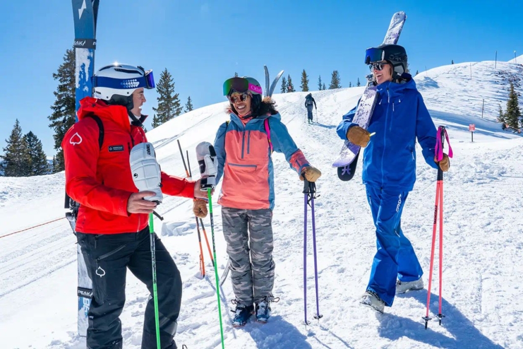 Three individuals on a snow-covered slope, equipped with skis, ready for snowboarding lessons and schools.