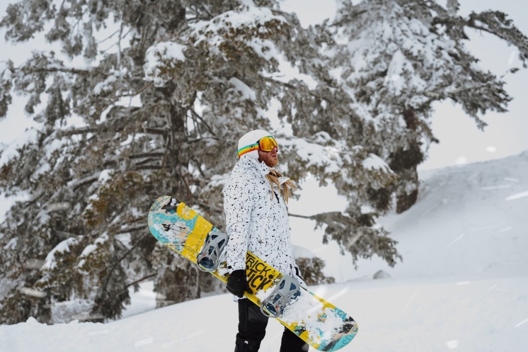 A person stands amidst the snow, featuring luxury snowboarding gear.