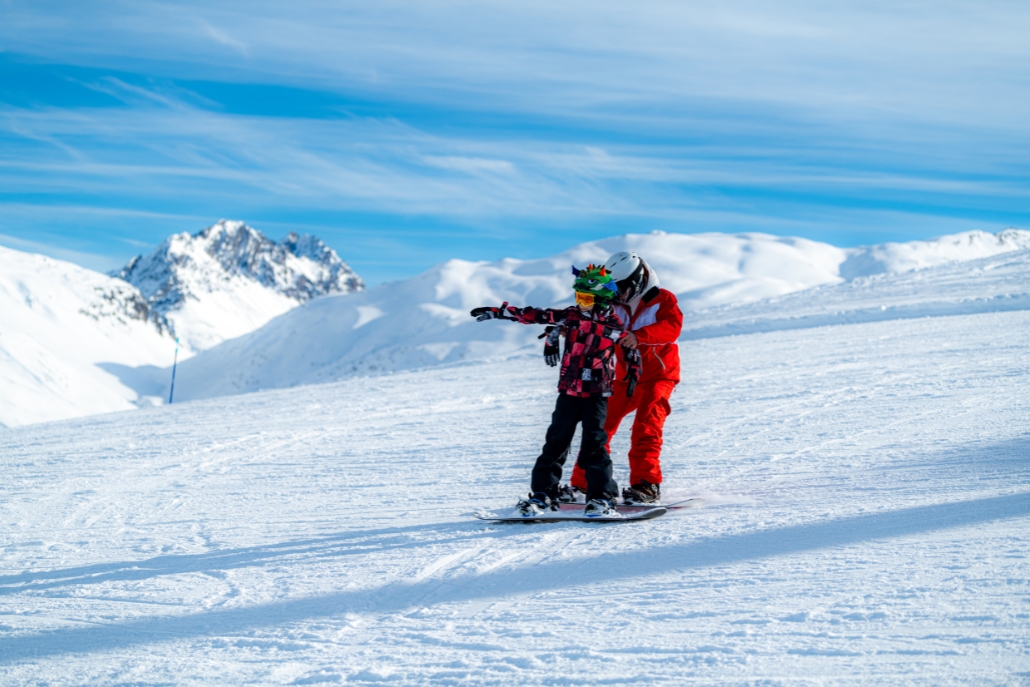 Two people snowboarding together on a snowy mountain in Aspen, representing snowboarding lessons and schools.