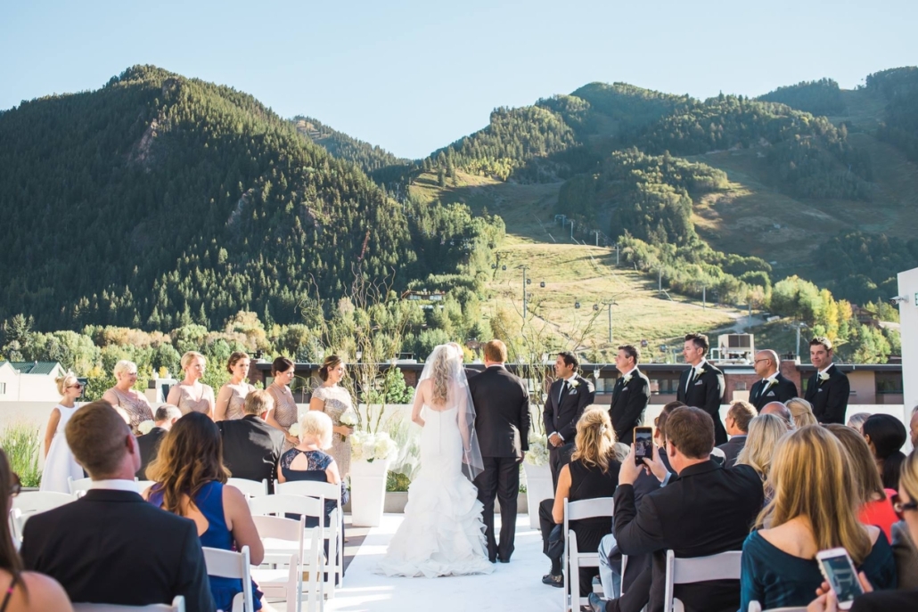 A picturesque wedding ceremony set in the mountains, with stunning peaks visible in the background, showcasing Aspen's beauty.
