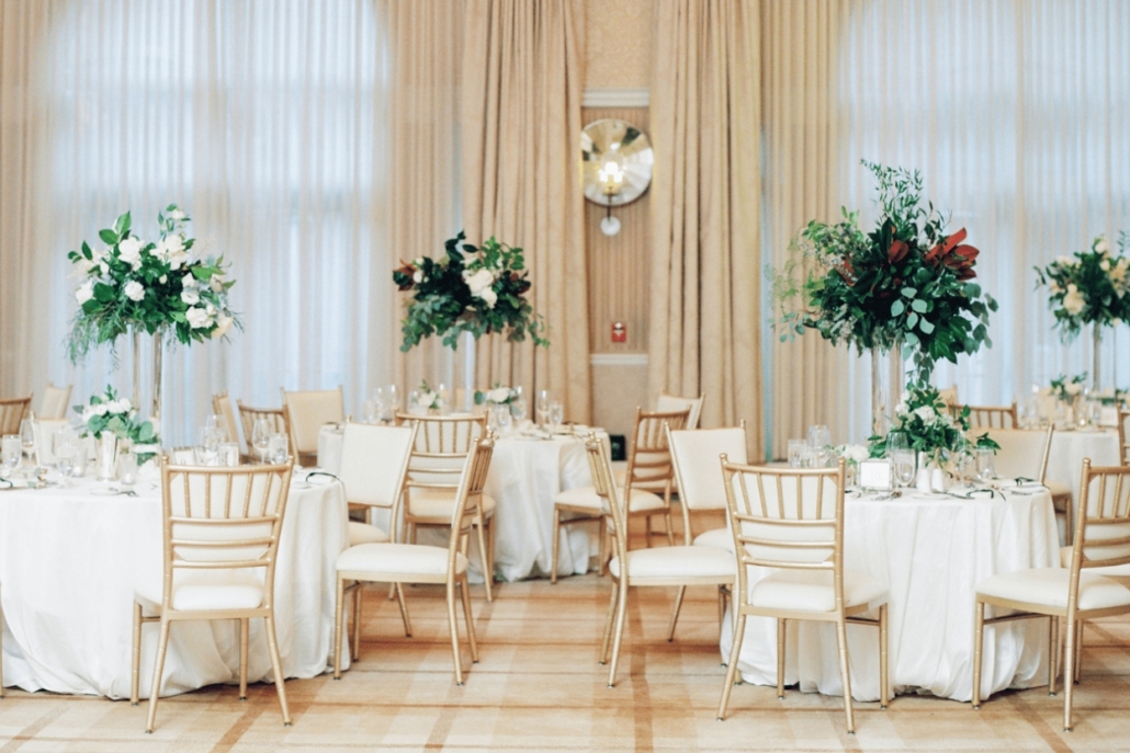 Elegant wedding reception at Hotel Jerome, showcasing white chairs and stunning tall floral arrangements throughout the room.