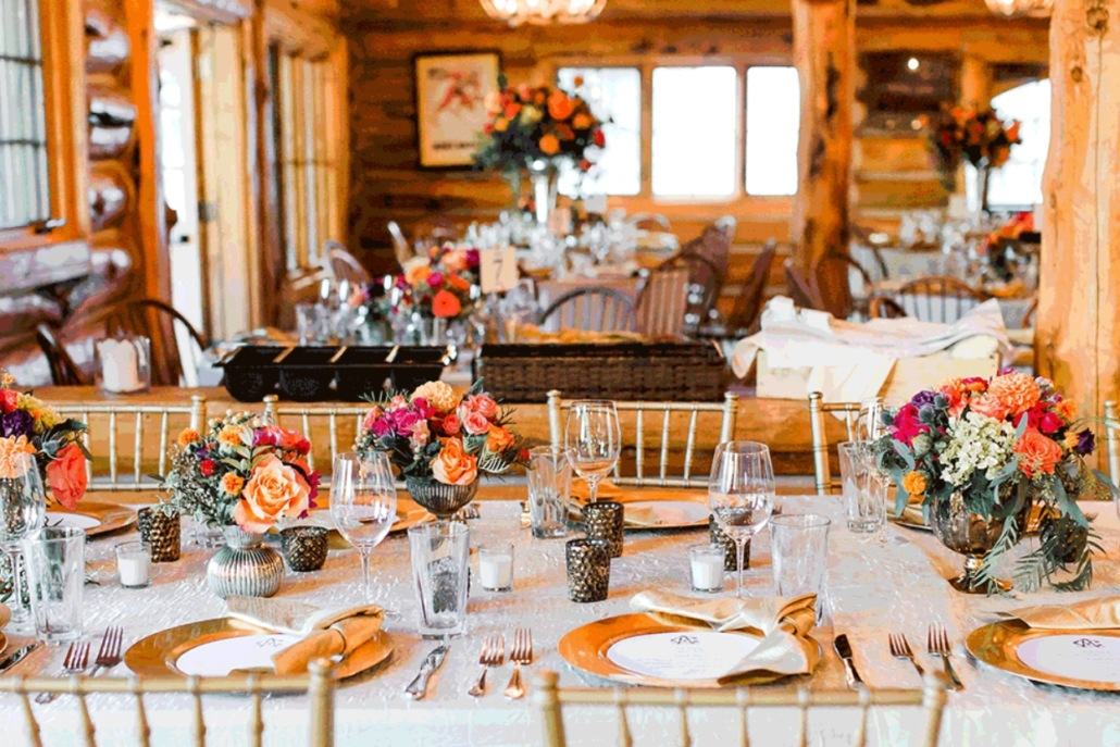 Elegant rustic wedding reception with vibrant gold and orange flowers, located at the scenic Pine Creek Cookhouse.