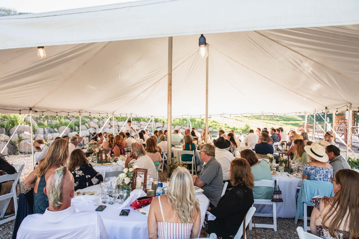 Guests gathered at tables inside a tent, celebrating a wedding in Aspen, showcasing the venue's charm and elegance.