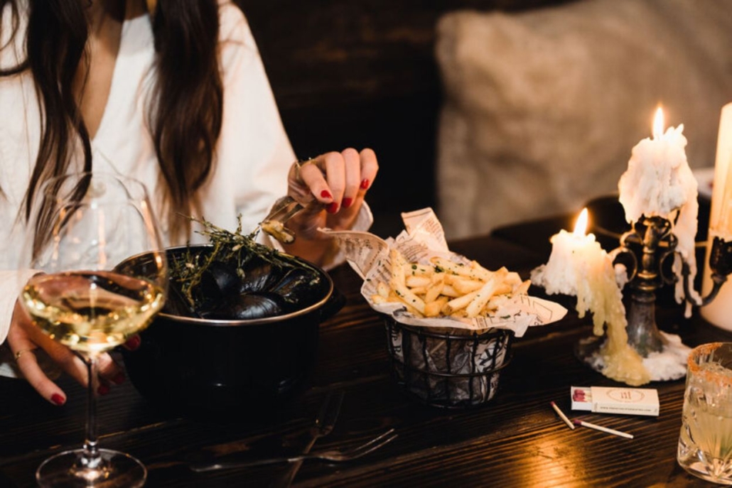 A woman enjoys a meal at a table in a cozy French Alpine bistro during November in Aspen.