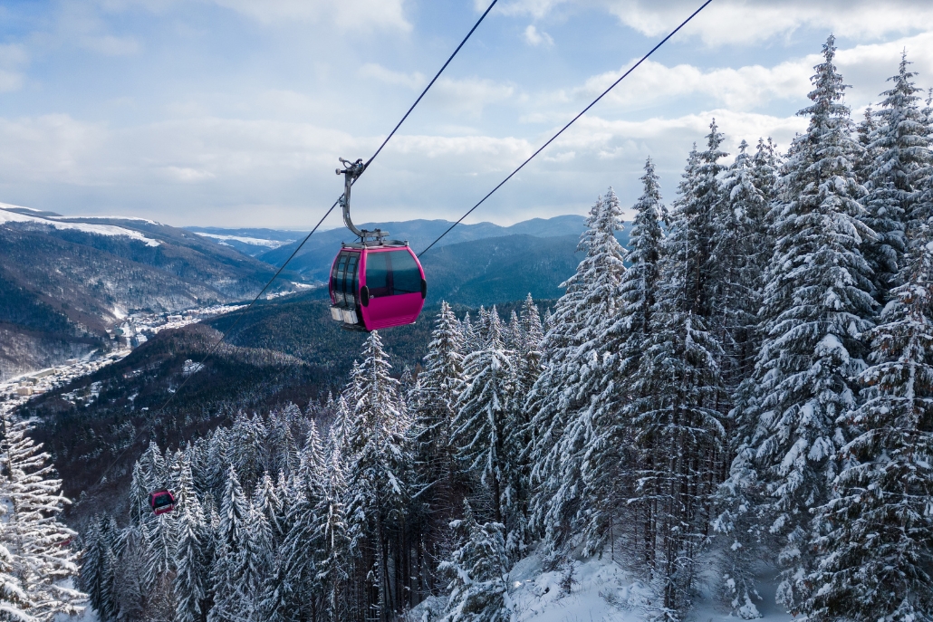 A gondola rises through a snowy landscape with trees, highlighting the picturesque scenery of Aspen in November.