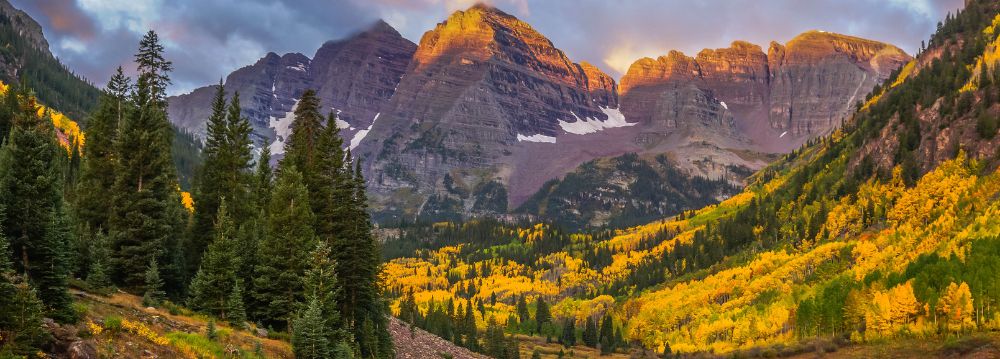 Sunlit mountains adorned with vibrant aspen trees, showcasing the beauty of November's golden hues.