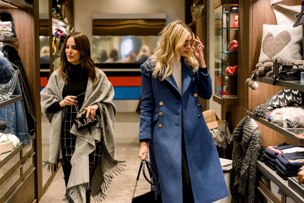 In an Aspen clothing store, two women examine various garments while shopping together.