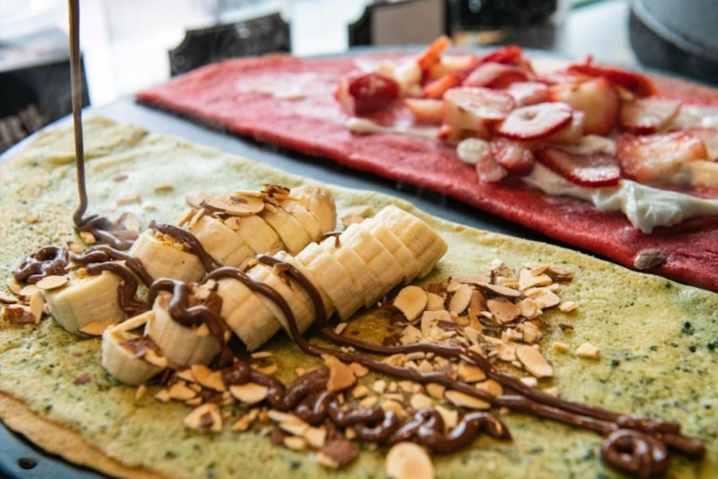 A delicious crepe filled with bananas and strawberries, drizzled with rich chocolate syrup, perfect for breakfast at Crepe Shack.