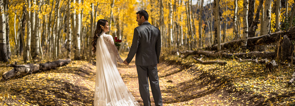 A bride and groom at their Aspen wedding ceremony, surrounded by beautiful scenery.