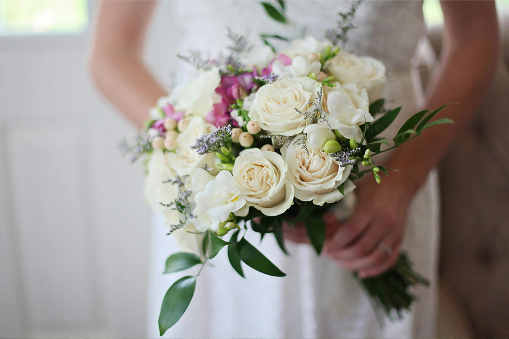 A close-up of a bride holding a delicate bouquet of flowers.