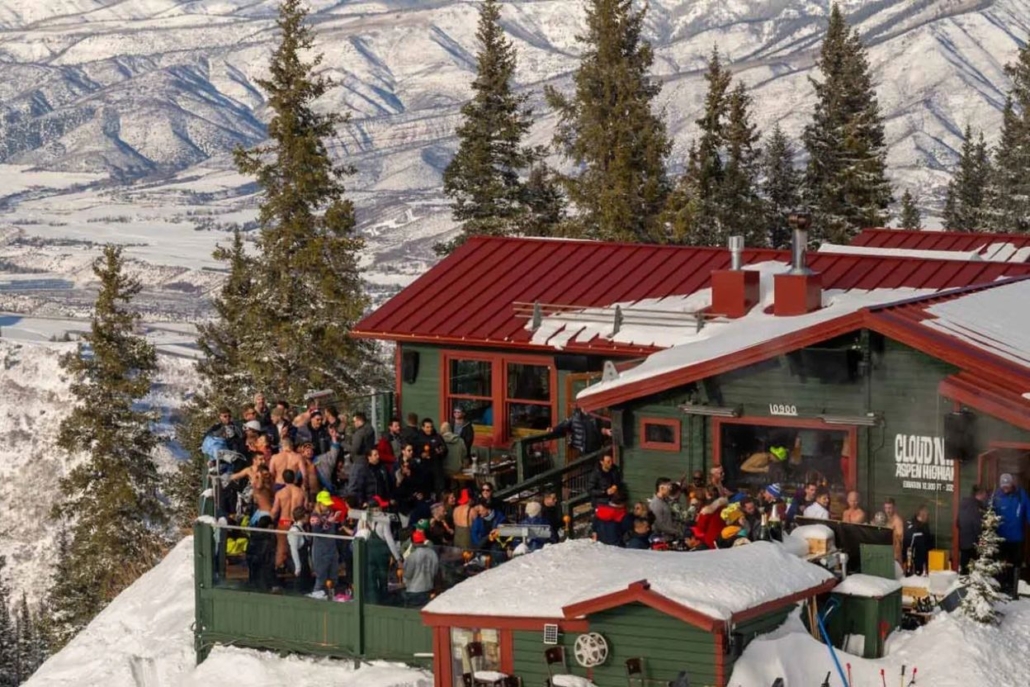 A lively group at Cloud Nine Alpine Bistro, celebrating luxury and sophistication at Aspen Après-Ski amidst a winter wonderland.