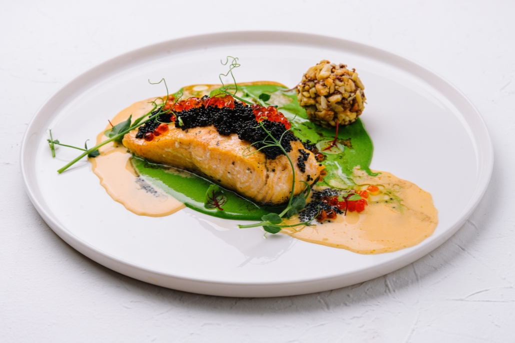 A gourmet dish of salmon and seasonal vegetables on a plate, presented at Matsuhisa Aspen during Aspen Après-Ski.