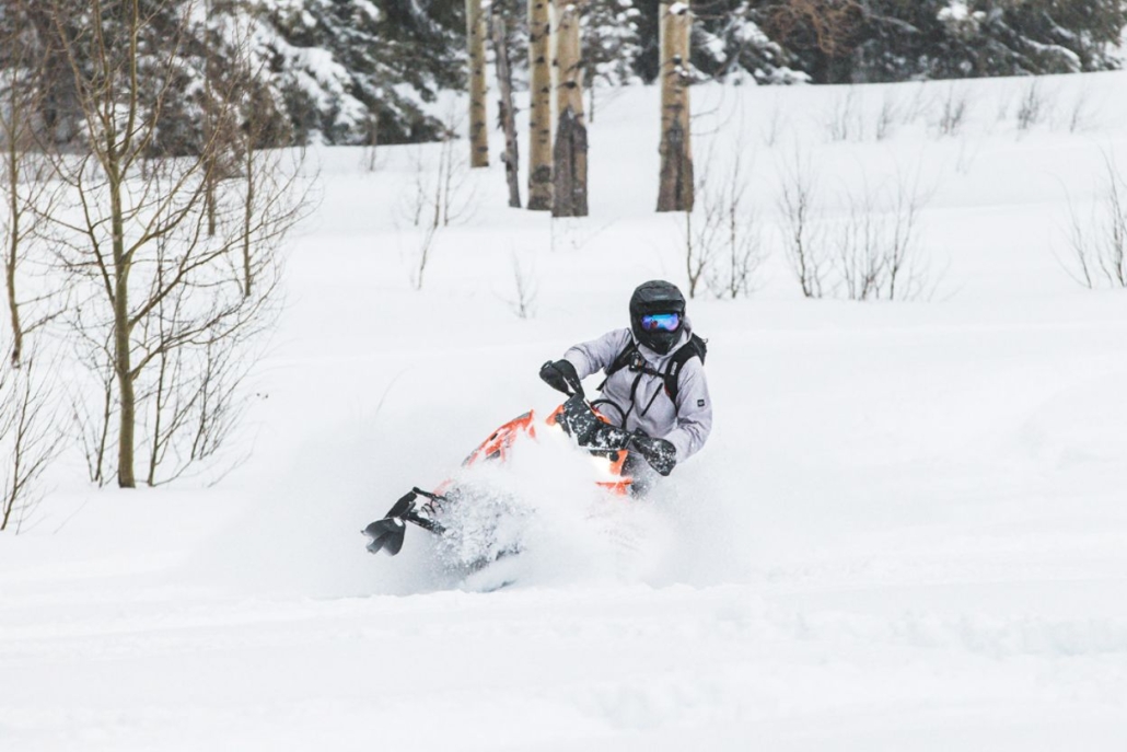 A person rides a snowmobile through the snowy landscape of Aspen in February, enjoying the winter adventure.