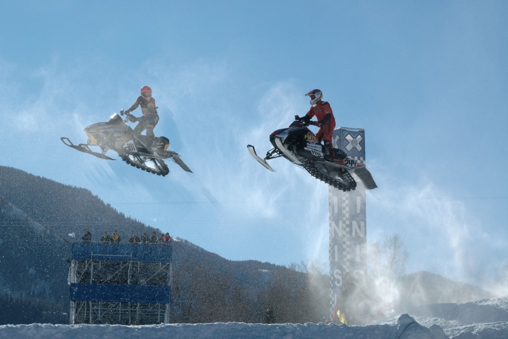 A thrilling moment of two people airborne on snowmobiles at Aspen's Winter X Games.