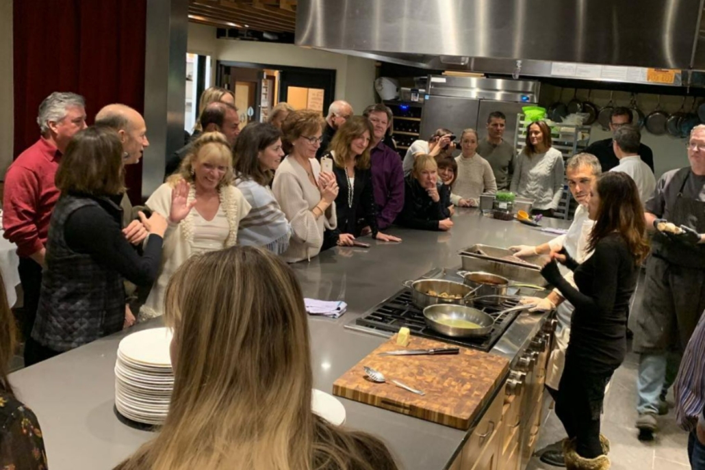 A group of individuals gathered around a kitchen counter during a culinary class in Aspen, January.