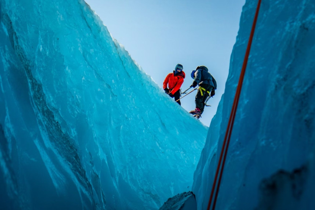 Two individuals skillfully climb a massive ice wall, embodying the excitement of Ice Climbing Adventures in Aspen.