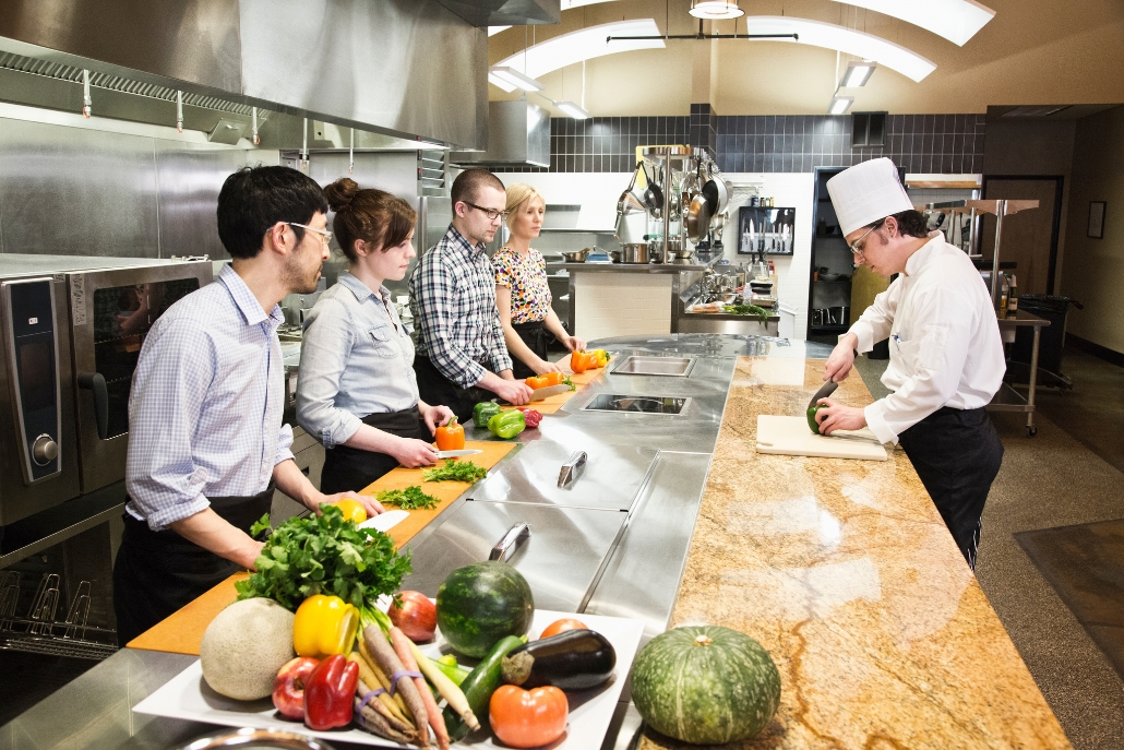 A group of people in a kitchen engaged in food preparation during a culinary class in Aspen, January.