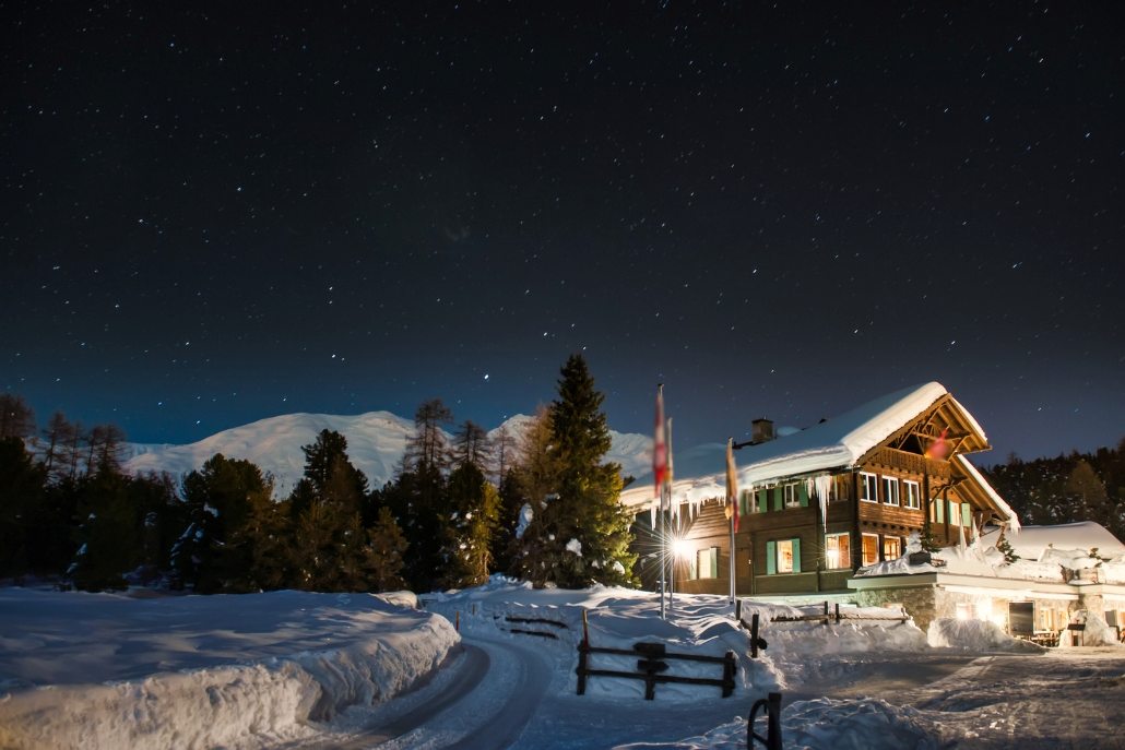 A charming lodge aglow at night with snow, creating a perfect dining atmosphere for Snowcat Dinner Tours in Aspen.