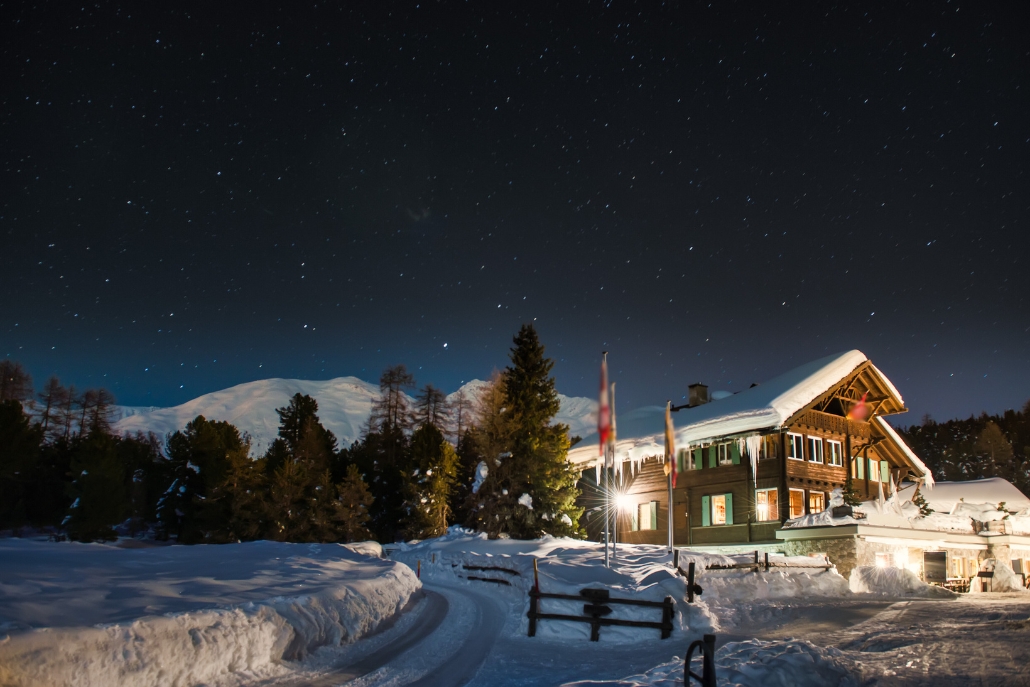 A charming lodge aglow at night with snow, creating a perfect dining atmosphere for Snowcat Dinner Tours in Aspen.