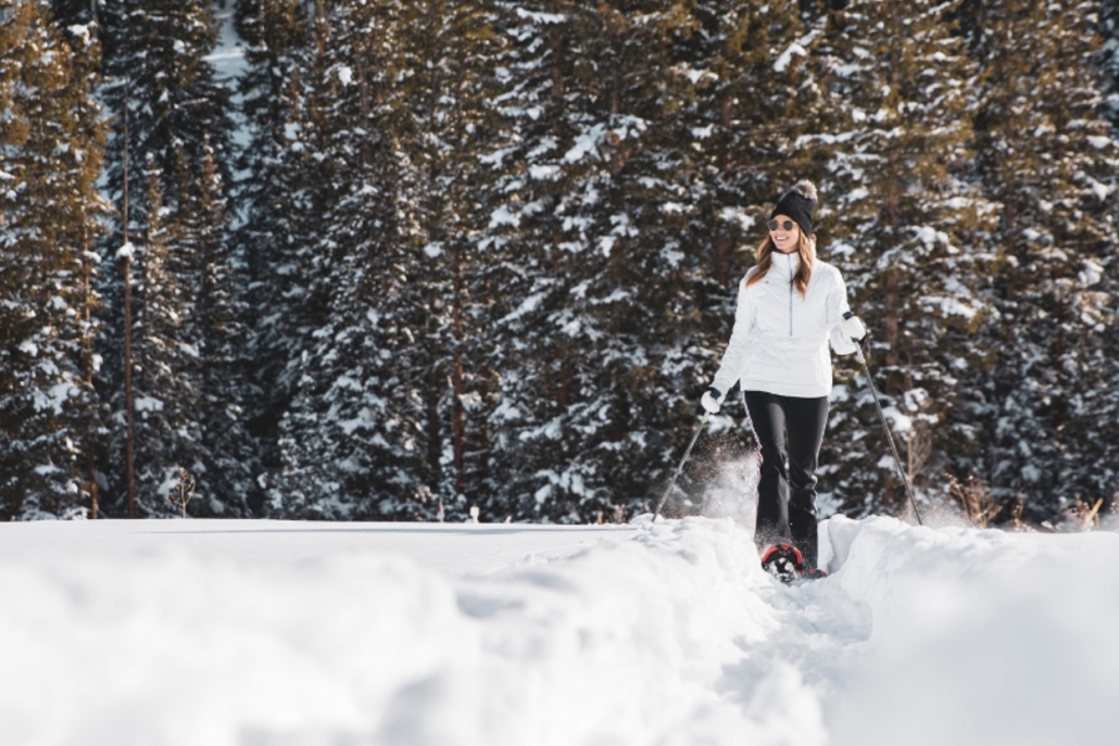 Woman snowshoeing through a snowy forest, enjoying Aspen in February and embracing active days off the slopes.