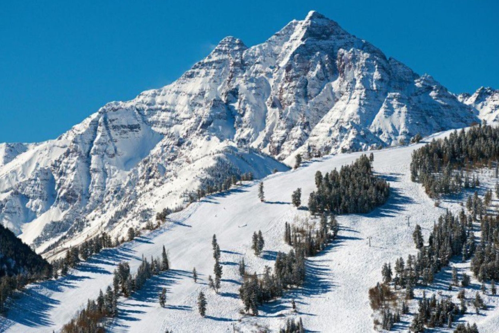 Snow-covered Aspen Mountain under a clear blue sky, setting the perfect backdrop for an unforgettable Aspen après-ski experience.