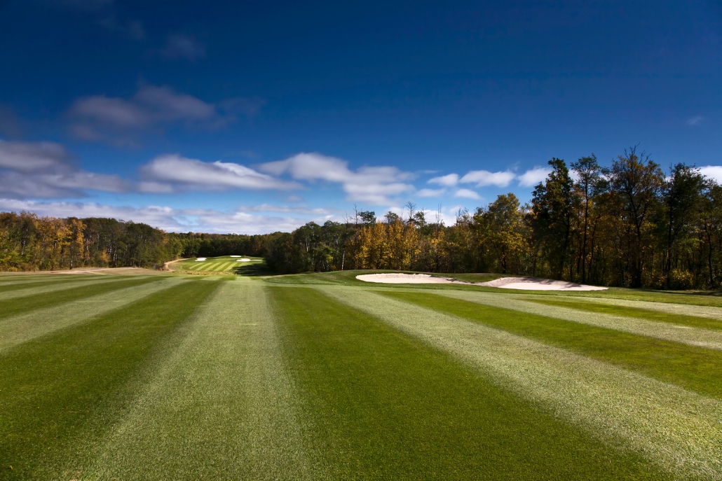 A panoramic shot of the golf course at Aspen Glen Club, highlighting its green grass and tree-lined surroundings.