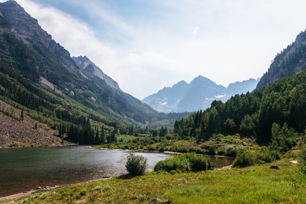 A picturesque lake framed by towering mountains and greenery, highlighting the scenic Roaring Fork Valley in Aspen.
