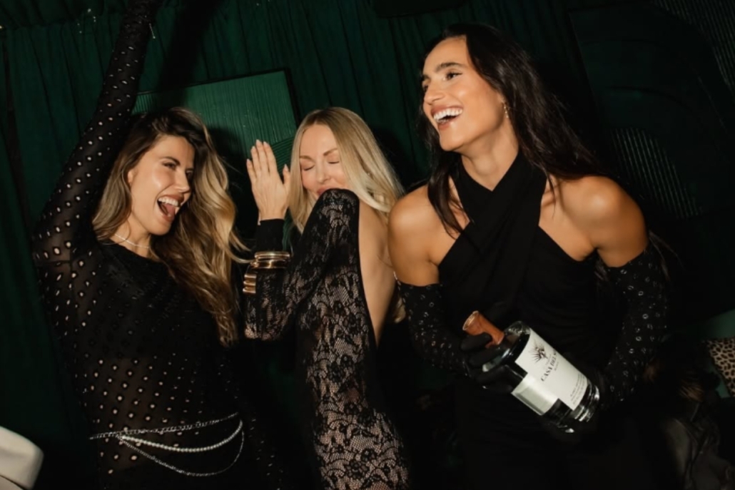 Three women dressed in black dance together at The Snow Lodge, celebrating a bachelorette party in Aspen.