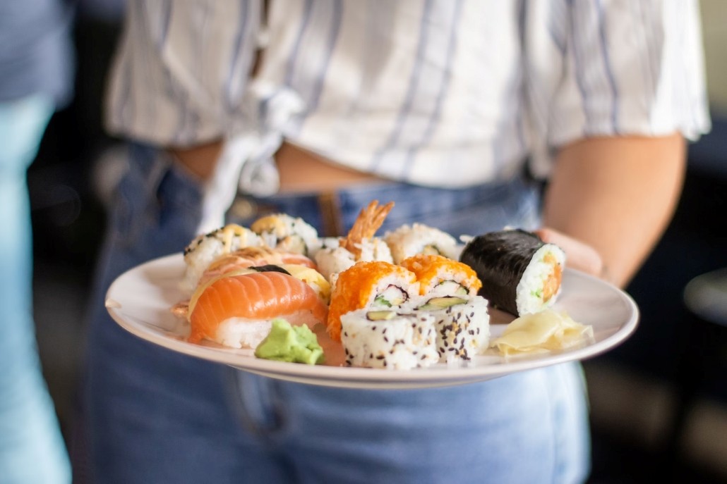 A woman with a plate of sushi at Matsuhisa, part of the Aspen family vacation experience.