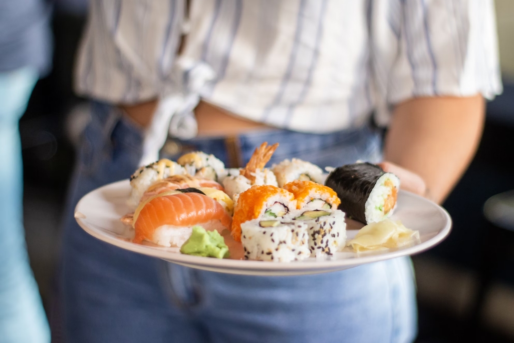 A woman with a plate of sushi at Matsuhisa, part of the Aspen family vacation experience.
