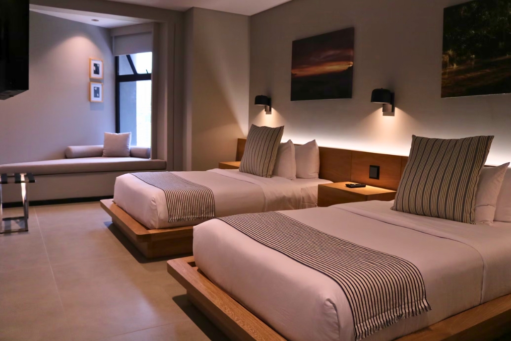 Two beds in a St. Regis Aspen Resort hotel room, highlighted by a spacious window offering scenic views.