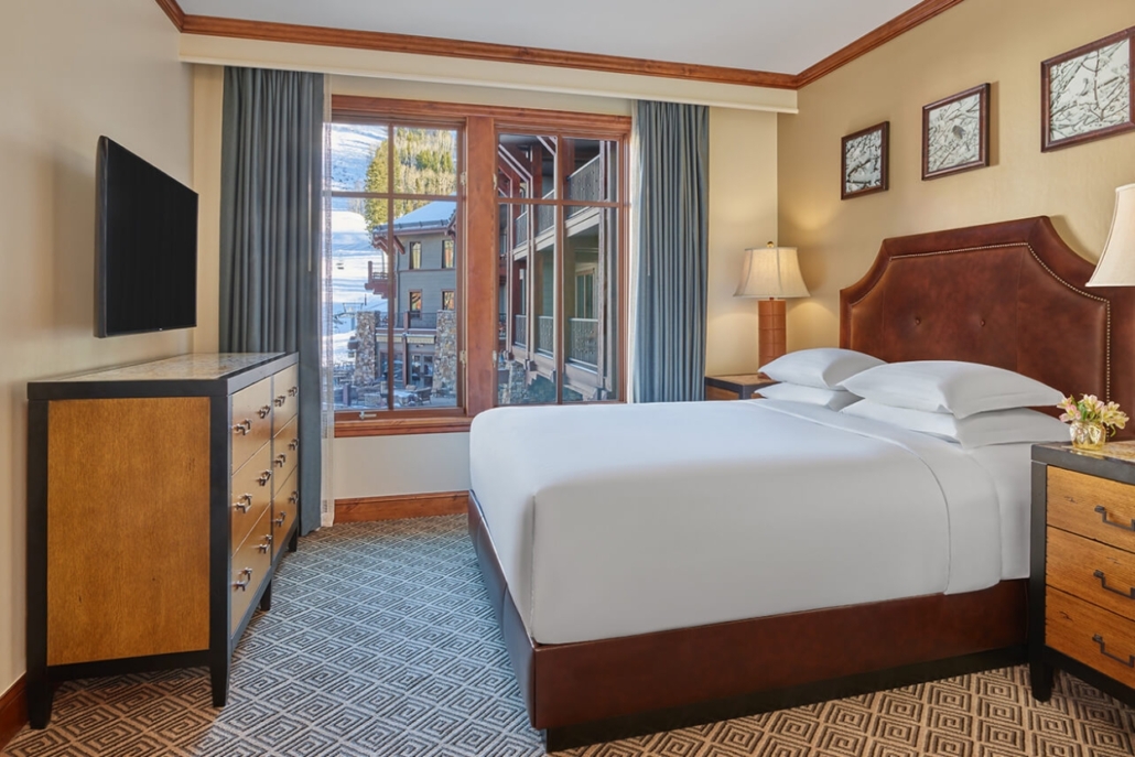Elegant hotel room in The Ritz Carlton Aspen, showcasing a bed, dresser, and a bright window, perfect for a bachelorette getaway.