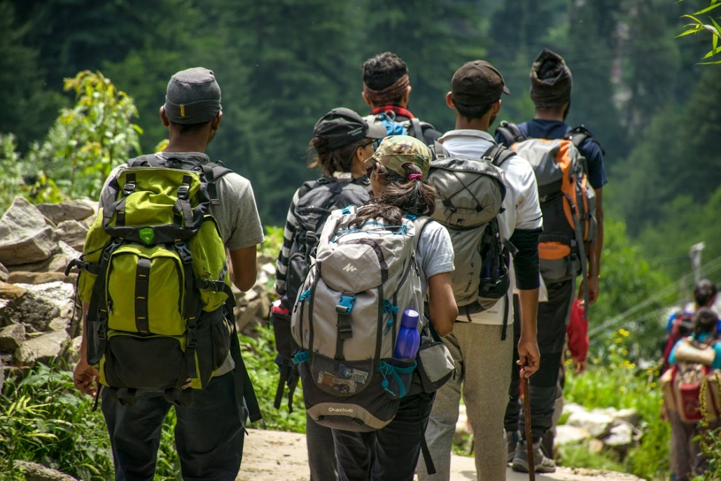 A group of hikers with backpacks walking up a scenic trail on a guided outdoor adventure in Aspen.