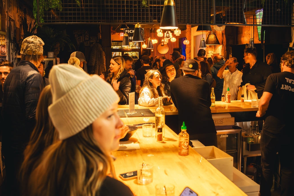 Guests relax at the wooden counter of Jimoto Aspen, immersed in the vibrant atmosphere of Aspen nightlife.