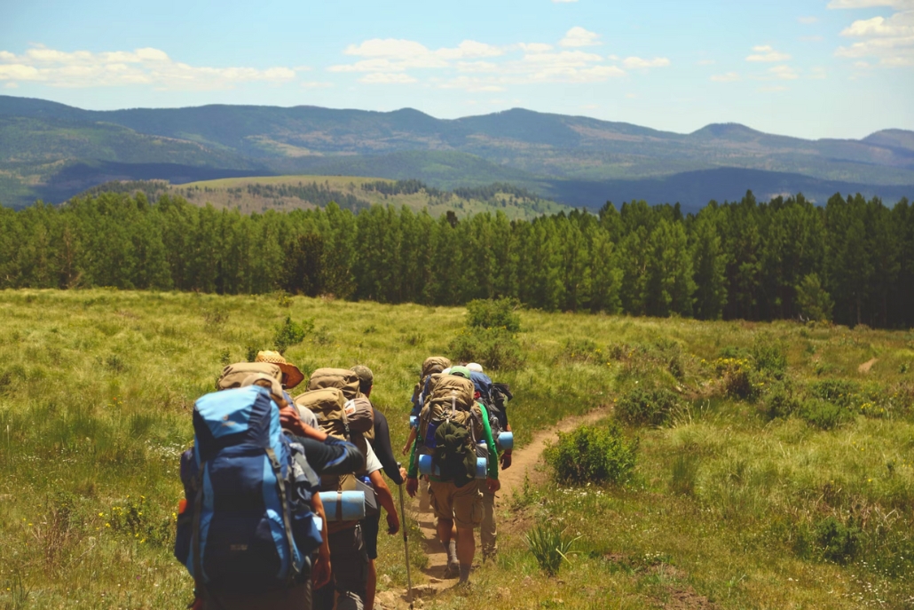 Enthusiastic hikers in stylish outdoor apparel navigating a picturesque mountain landscape, embodying Aspen's adventure lifestyle.